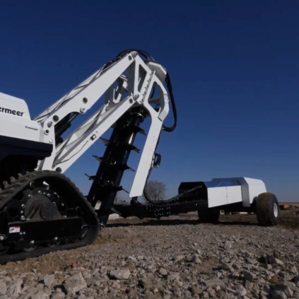 O equipamento, pintado de branco com a marca "Excavator Interlune Vermeer" visível na lateral, possui esteiras robustas e um braço articulado com sistema de corte ou perfuração. A estrutura futurista indica aplicações avançadas em ambientes desafiadores, como mineração ou até missões lunares. O rótulo “Prototype” confirma que se trata de um modelo experimental em fase de testes em solo terrestre.